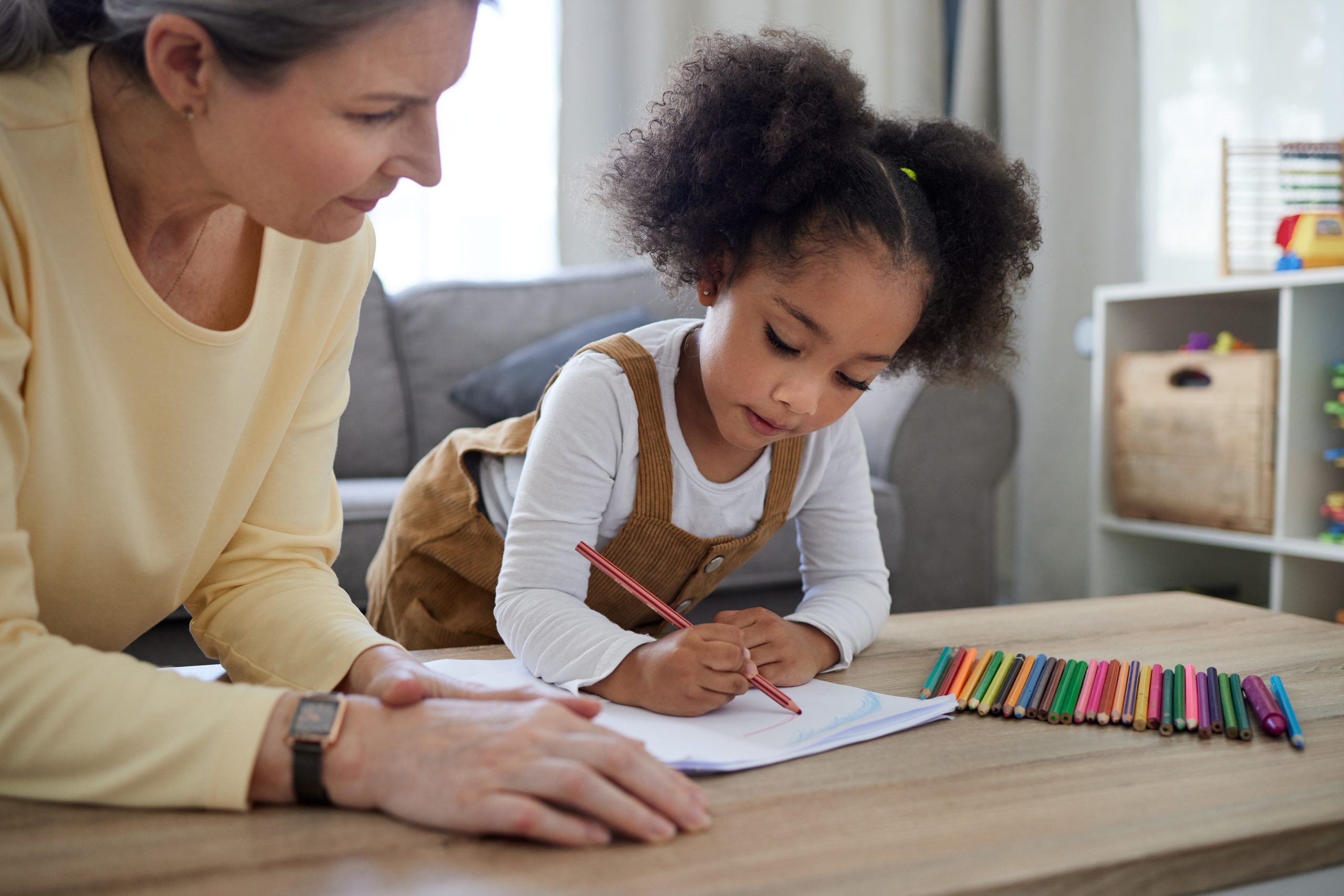 Neuropsychologue accompagnant une jeune enfant lors d’une activité de dessin et d’évaluation cognitive.